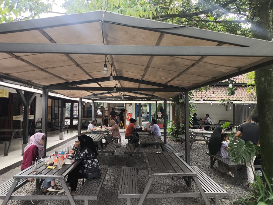 Area makan outdoor dengan meja panjang di bawah kanopi