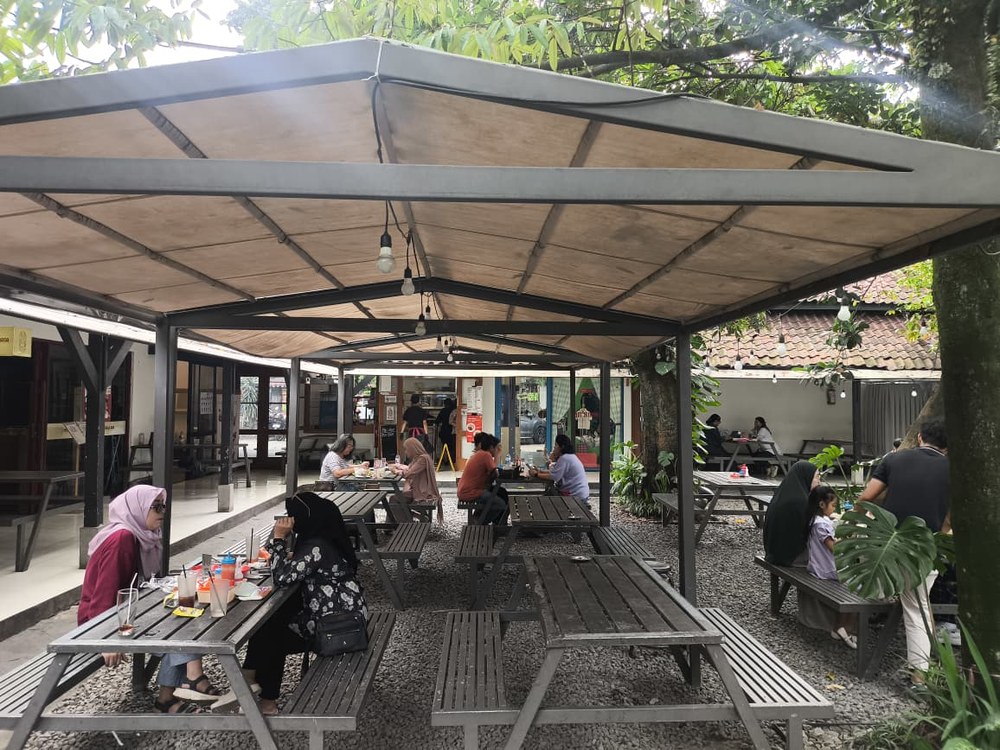 Area makan outdoor Baso Laswi dengan meja kayu panjang dan atap kanopi